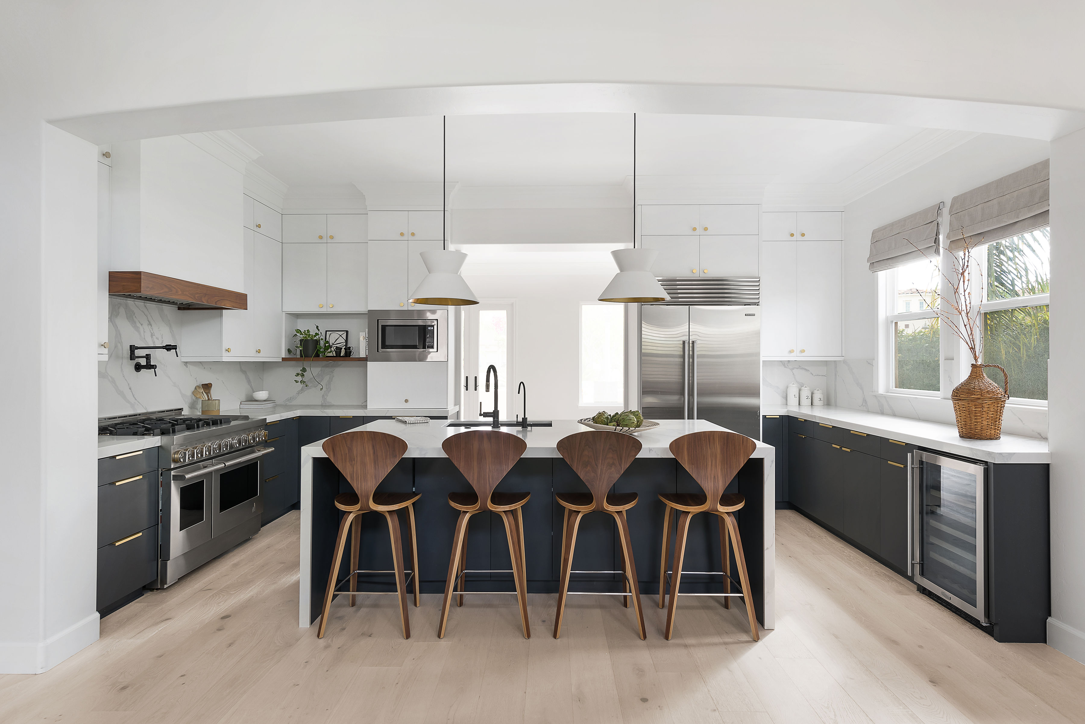 Contemporary kitchen featuring white cabinets, dark accents, and a central island with bar stools.