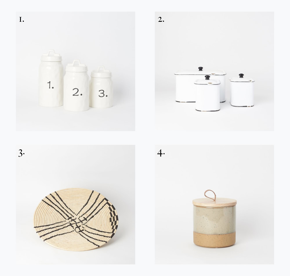 Set of three white ceramic canisters with black lids for kitchen storage.