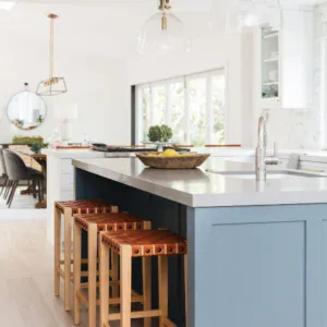 Bright blue kitchen island with wooden bar stools and modern lighting fixtures.