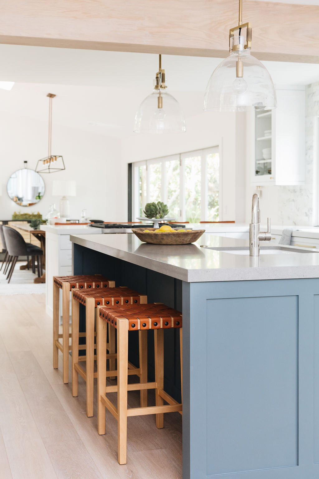 Bright blue kitchen island with wooden bar stools and modern lighting fixtures.