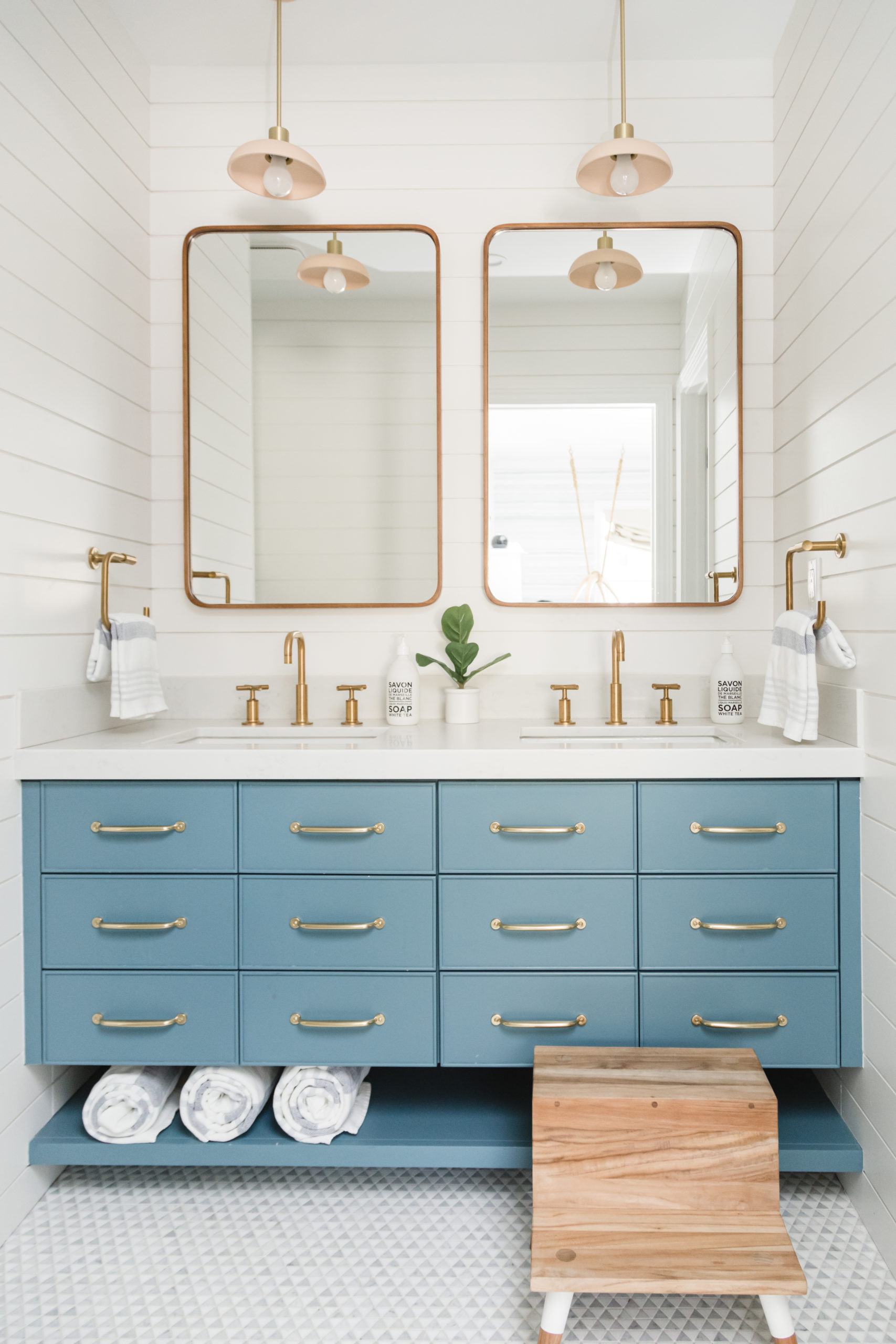 Elegant blue bathroom vanity with gold hardware and twin mirrors.