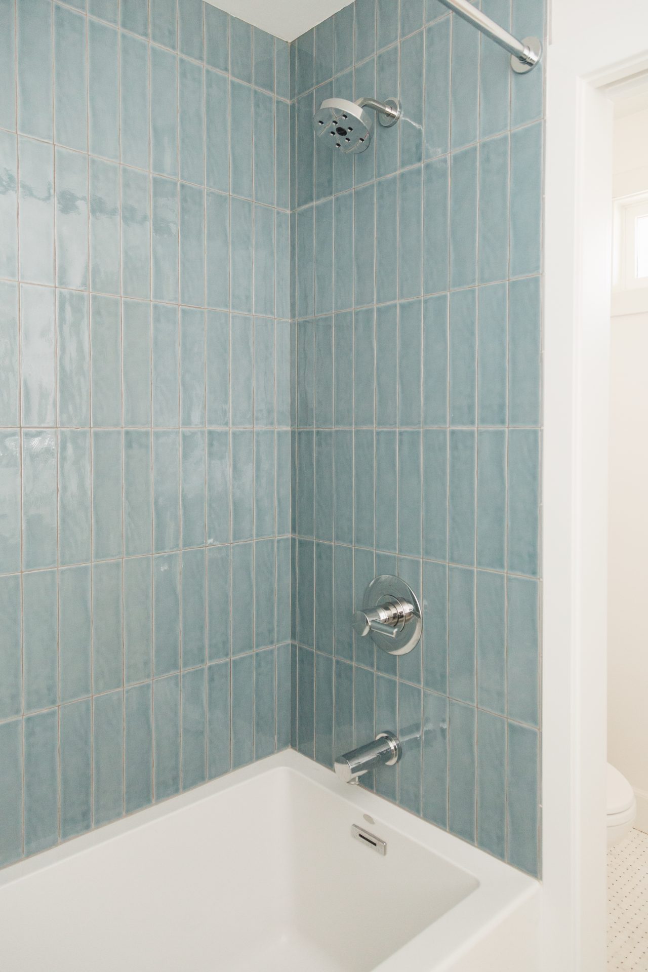 Blue tiled shower wall with modern fixtures at South Harlow Interiors.
