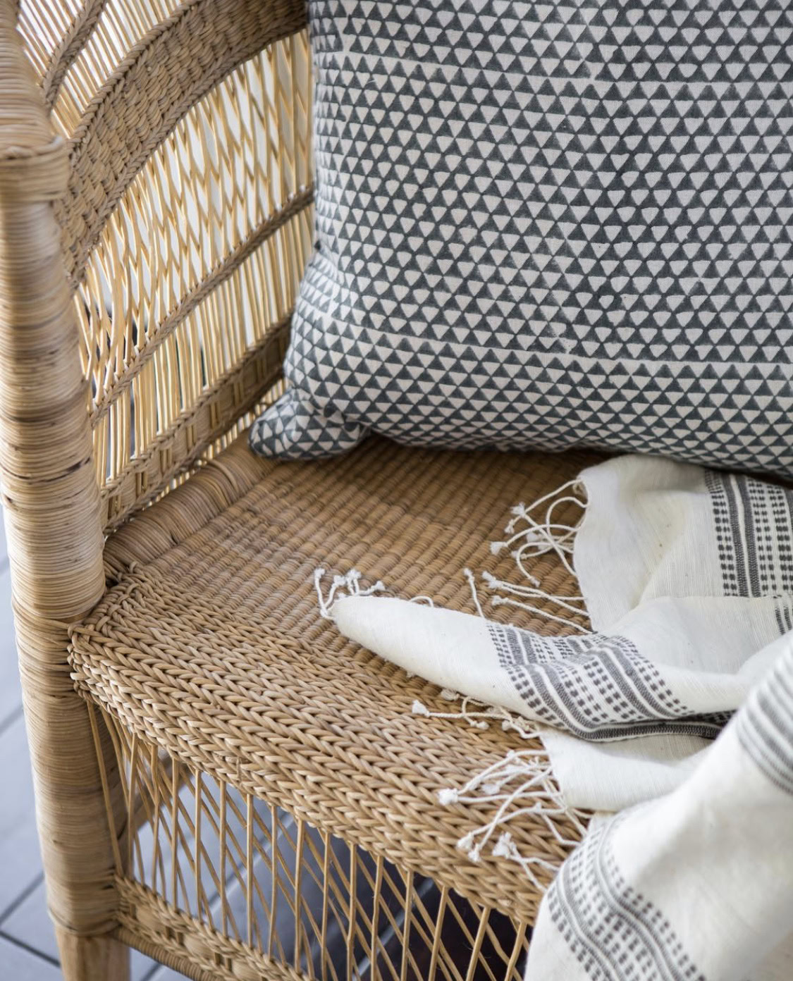 Rattan chair with patterned cushion and throw blanket, perfect for summer outdoor upgrades.