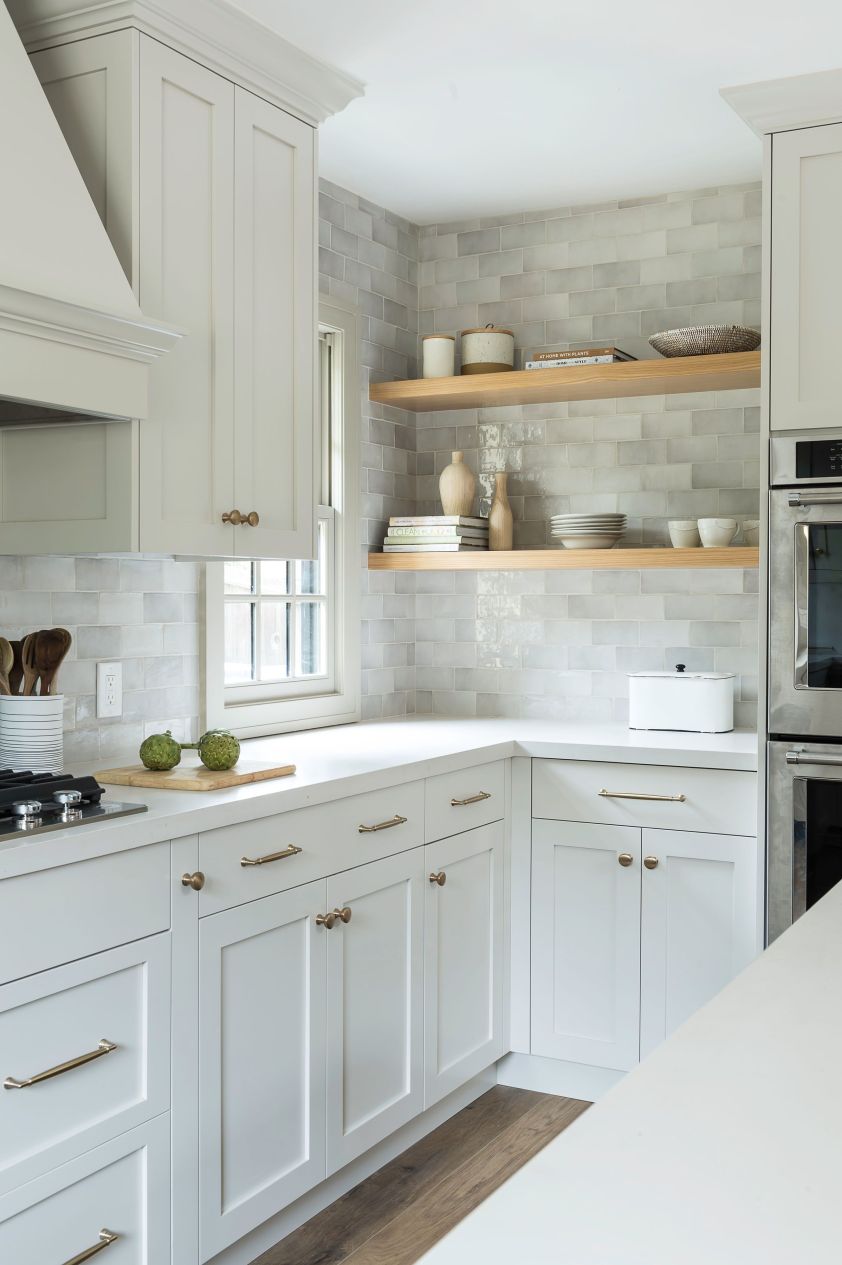Bright white kitchen featuring open wooden shelves and a gray brick backsplash, perfect for stylish.