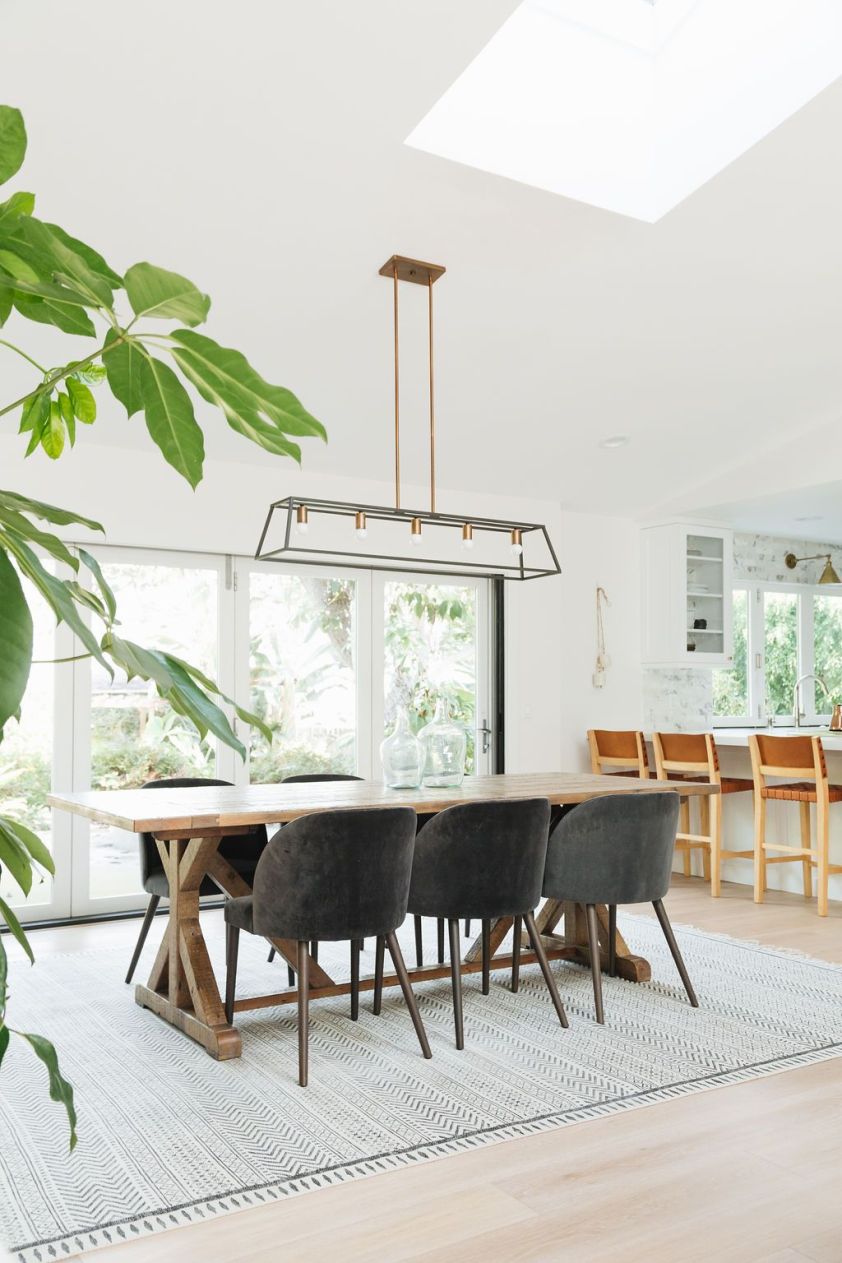 Elegant dining area featuring a stylish rug, wooden table, and comfortable chairs illuminated by nat.