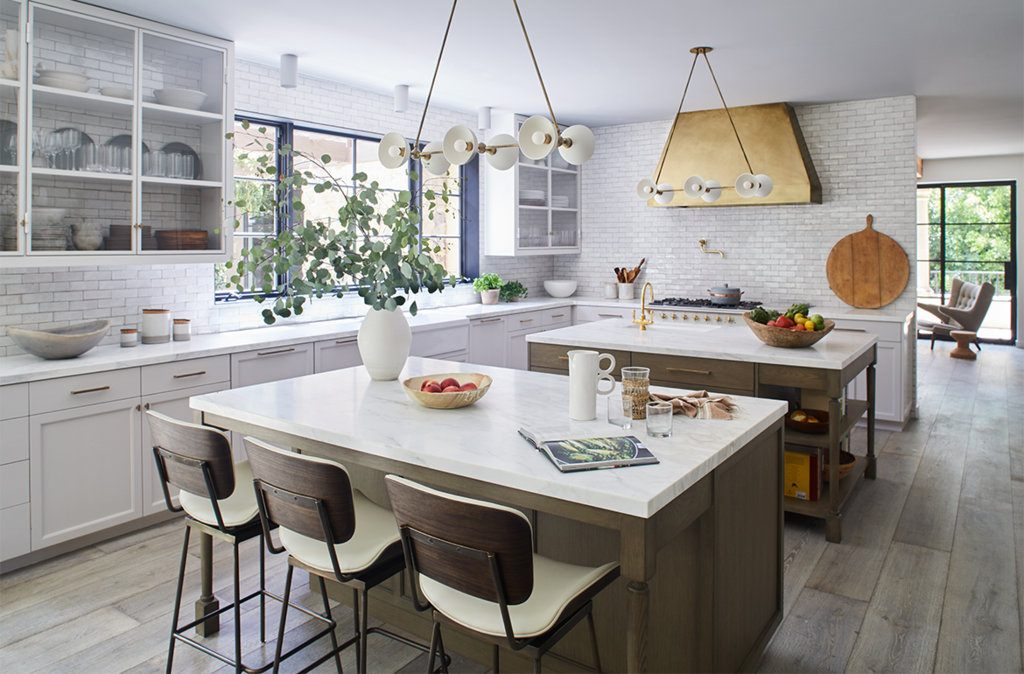 Bright, stylish kitchen featuring white cabinetry, large island, and modern lighting fixtures.