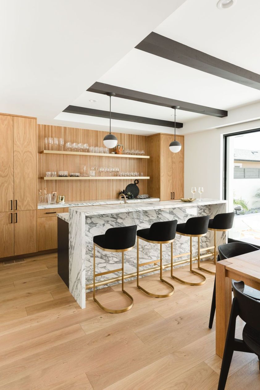Modern kitchen interior with marble island and black bar stools.