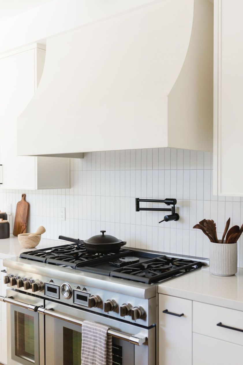 Bright white kitchen featuring a gas stove and minimalist design.