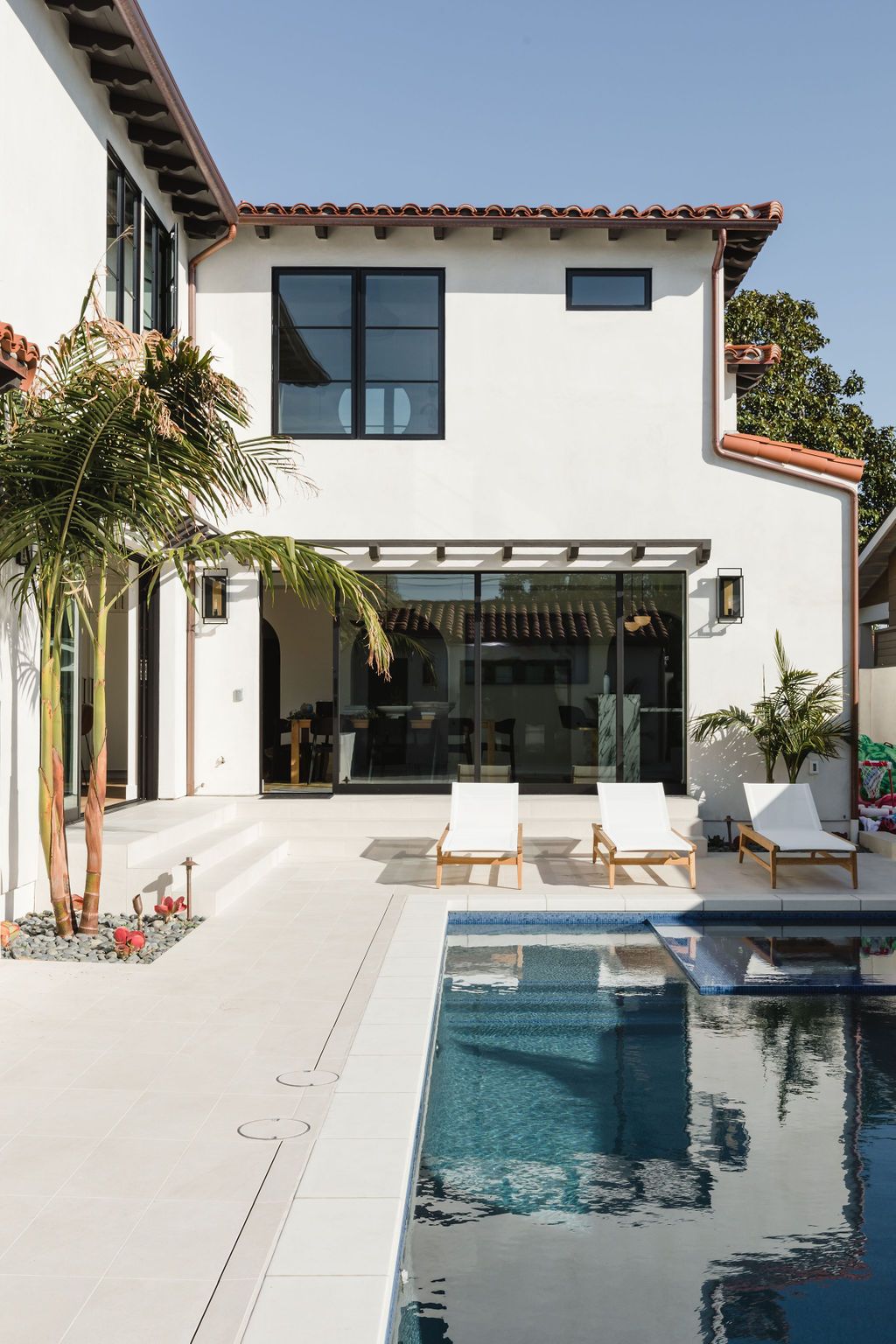 Elegant Spanish-style home exterior with a swimming pool and outdoor lounge area.