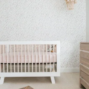 Modern nursery room with white crib and textured wallpaper, perfect for little ones' comfort and sty.