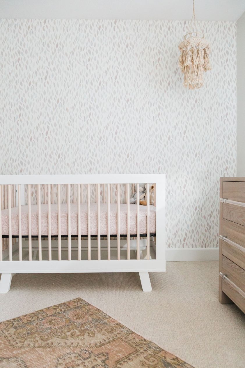 Modern nursery room with white crib and textured wallpaper, perfect for little ones' comfort and sty.