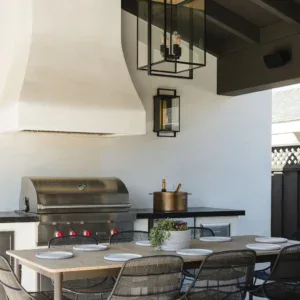 Outdoor kitchen with grill and dining table for entertaining guests.