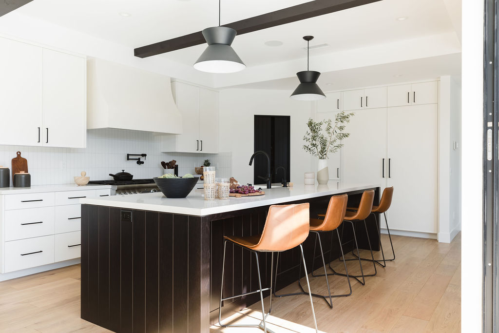 Bright and stylish kitchen featuring a black island, white cabinetry, and contemporary lighting fixt.