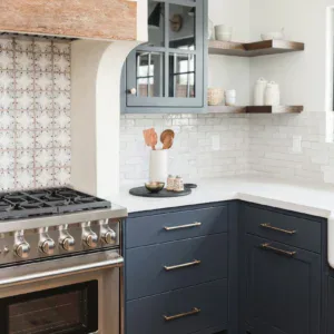 Navy kitchen cabinets with open shelves and white tile backsplash.