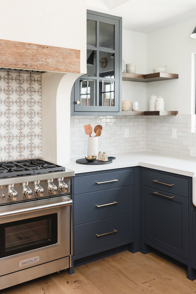 Navy kitchen cabinets with open shelves and white tile backsplash.