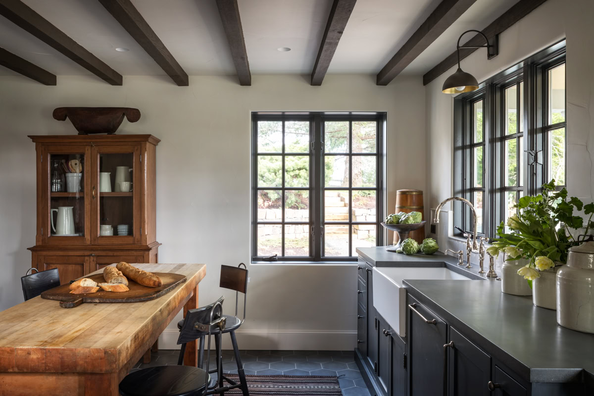 Modern kitchen featuring exposed wooden ceiling beams and large windows.
