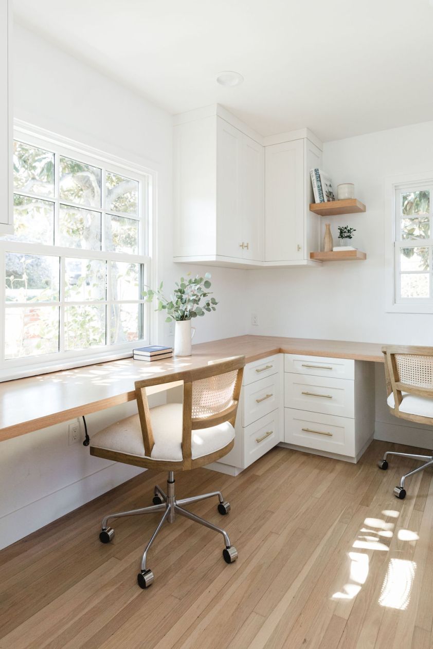 Bright white office desk with ergonomic chairs in a sunny workspace.