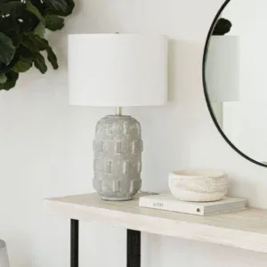 Elegant round table lamp with textured base and white shade for modern interiors.