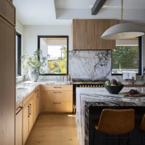 Bright modern kitchen featuring marble countertops and wooden cabinetry.