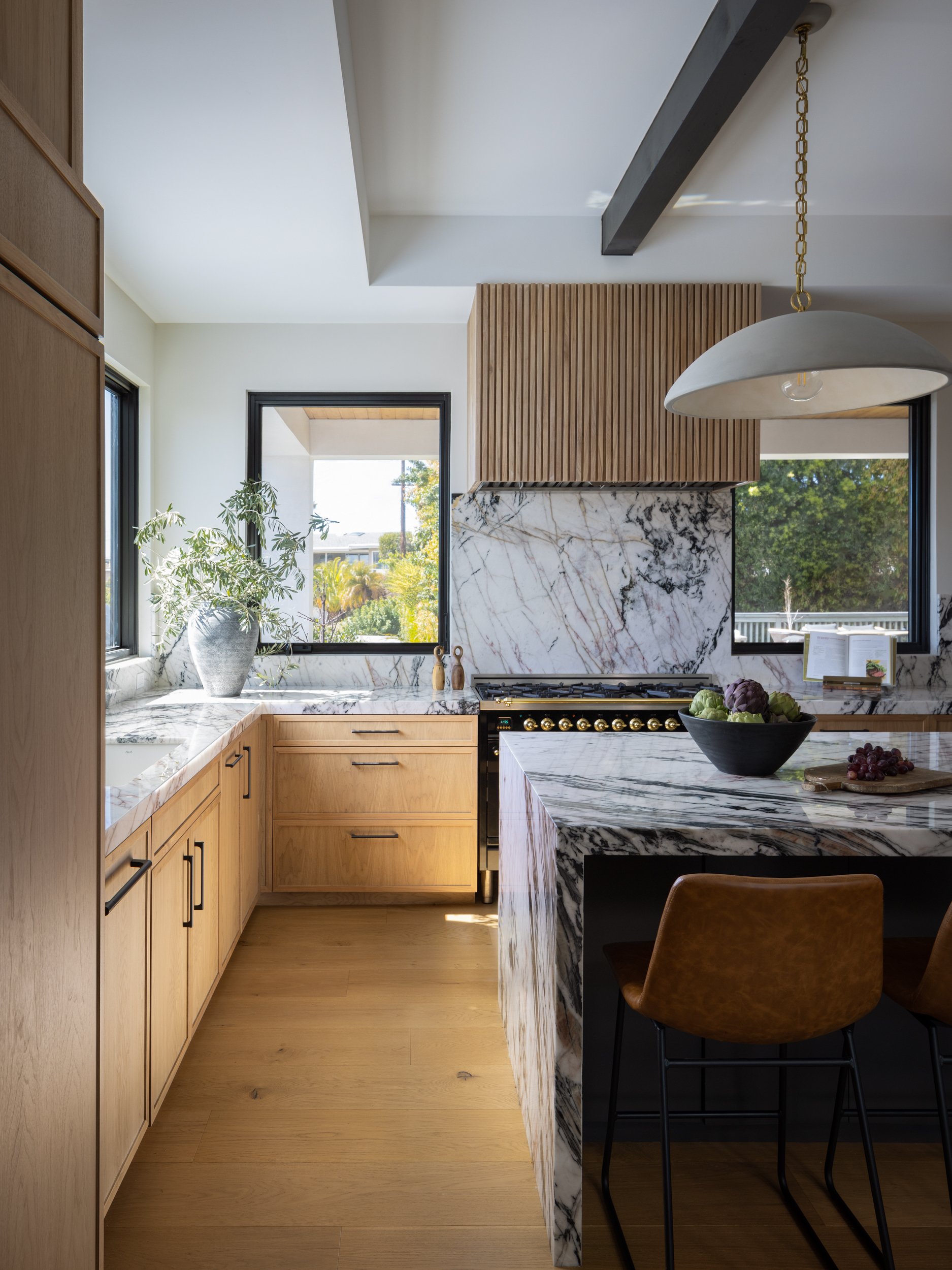 Bright modern kitchen featuring marble countertops and wooden cabinetry.