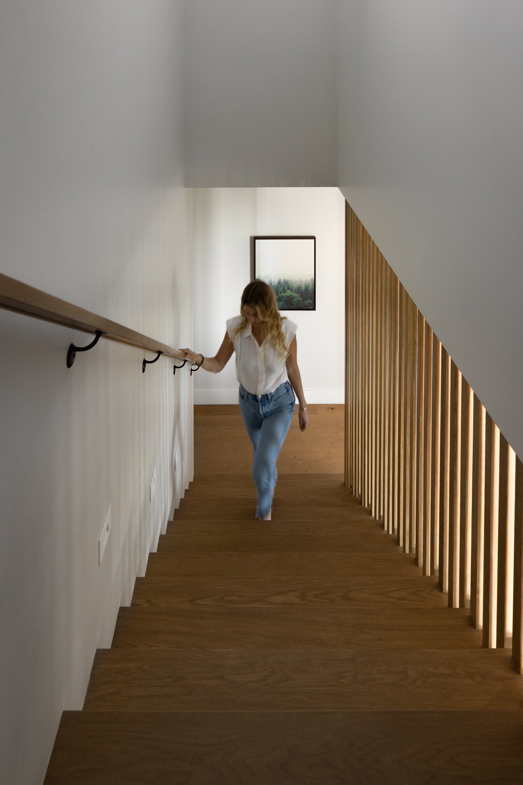 Modern staircase with wooden steps and sleek handrail in contemporary home.