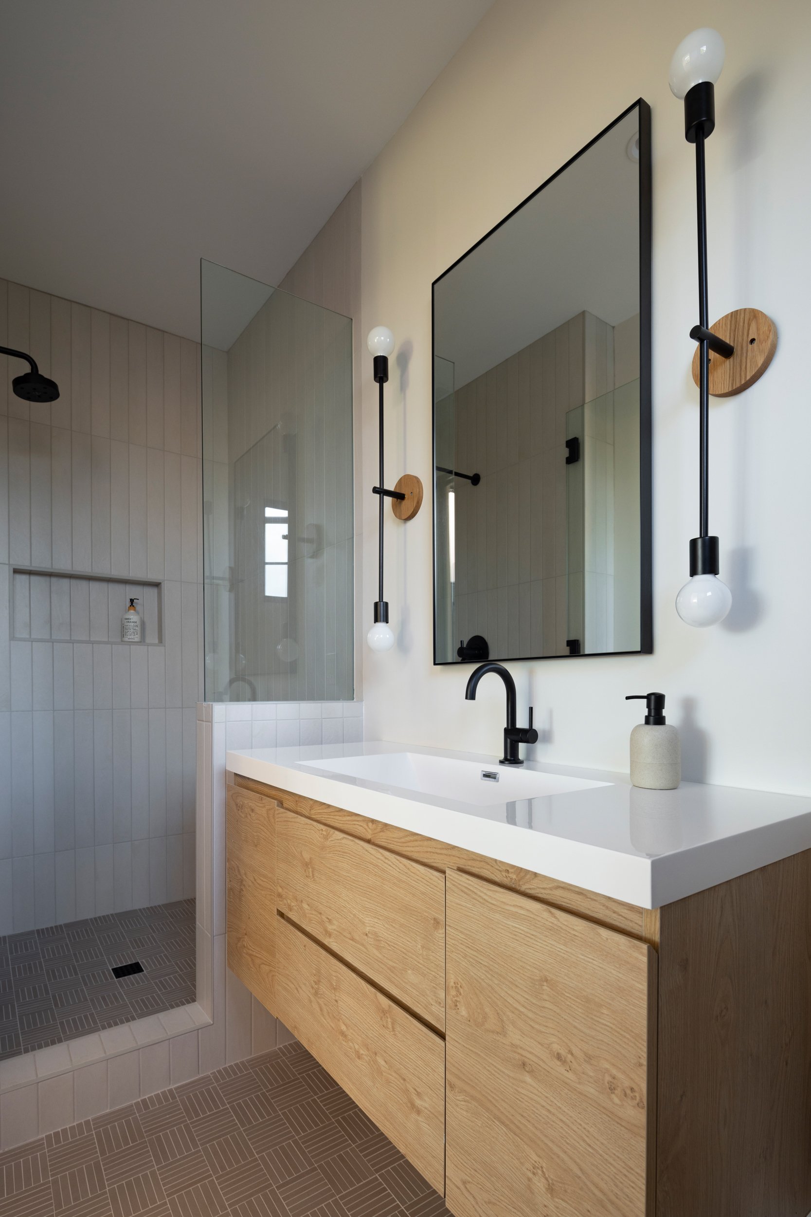 Bathroom vanity with wooden drawers, black faucet, and mirror.
