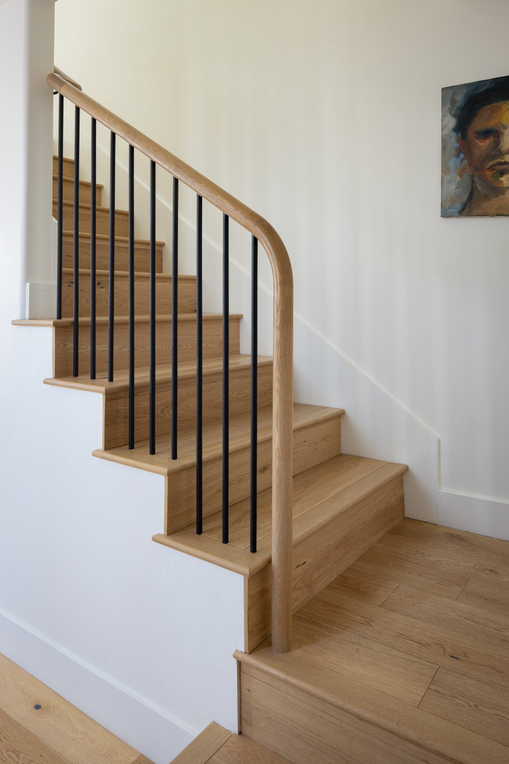 Elegant wooden staircase with black metal balusters in a modern home.