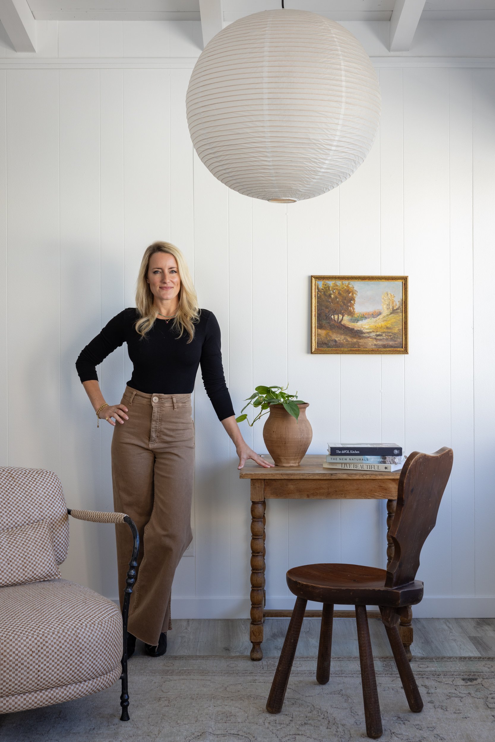 Interior design team member standing in a stylish room with a large paper lantern, artwork, and cozy.