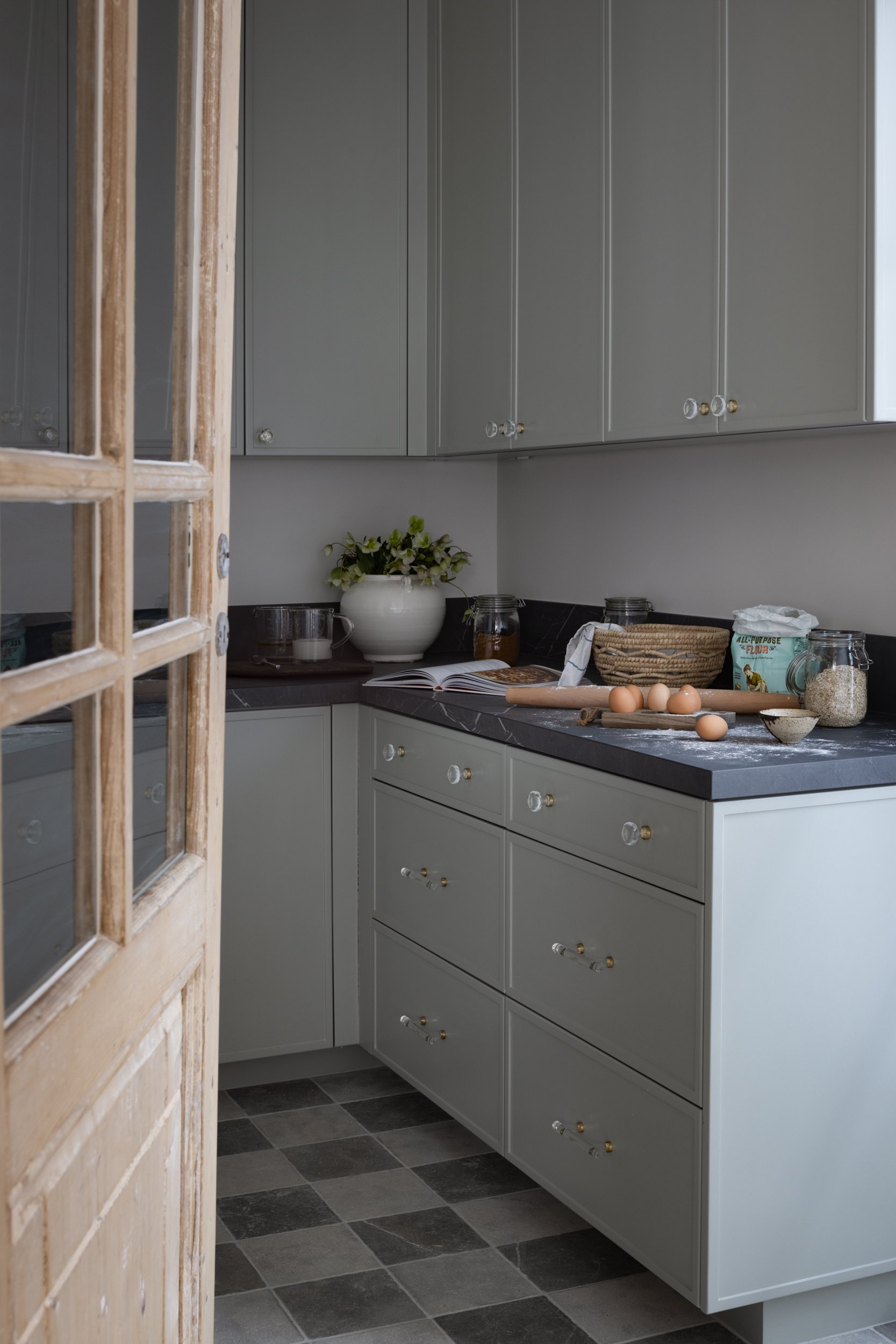 Modern grey kitchen cabinets with black countertops and decorative items.