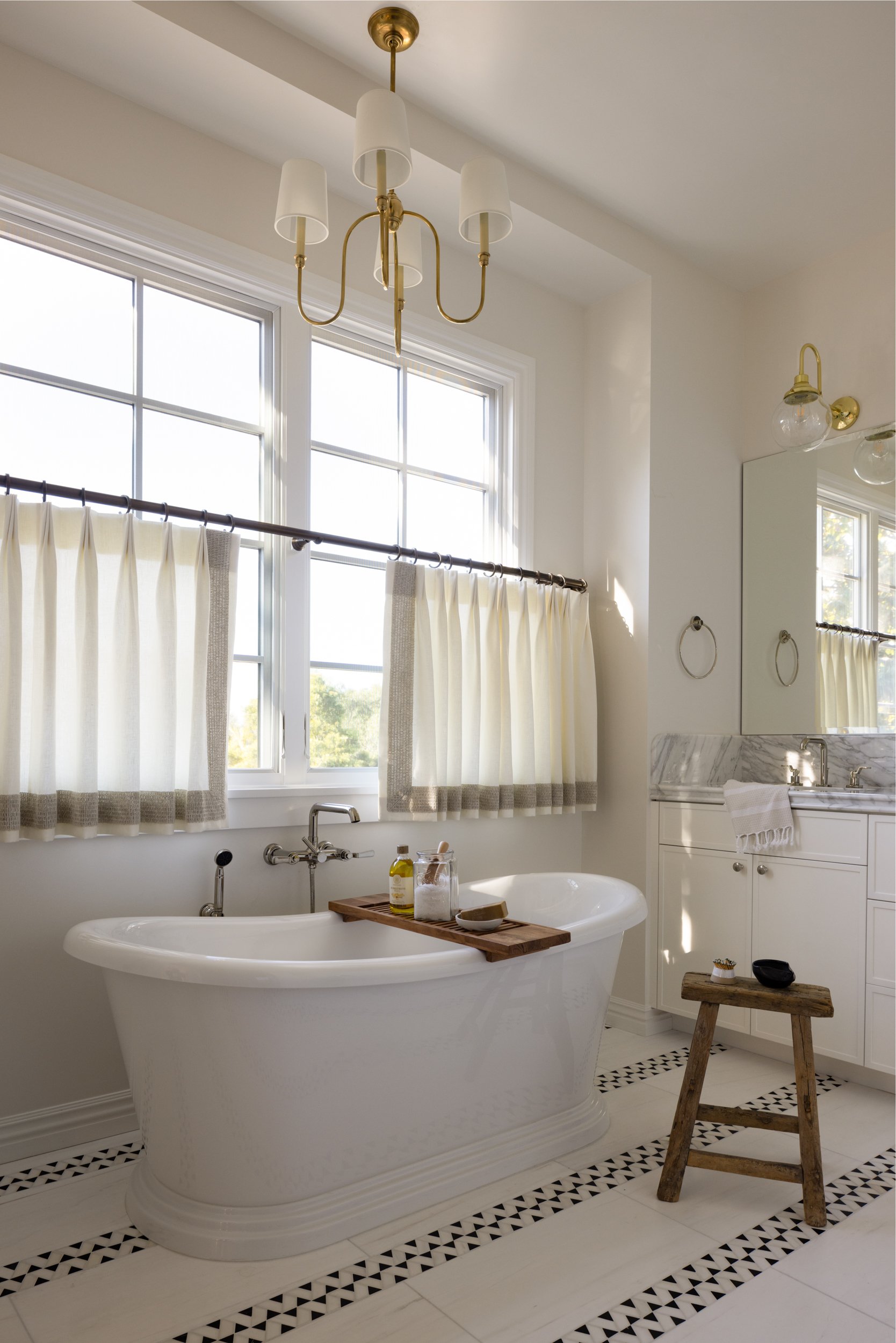 Elegant freestanding bathtub in bright bathroom with large windows.