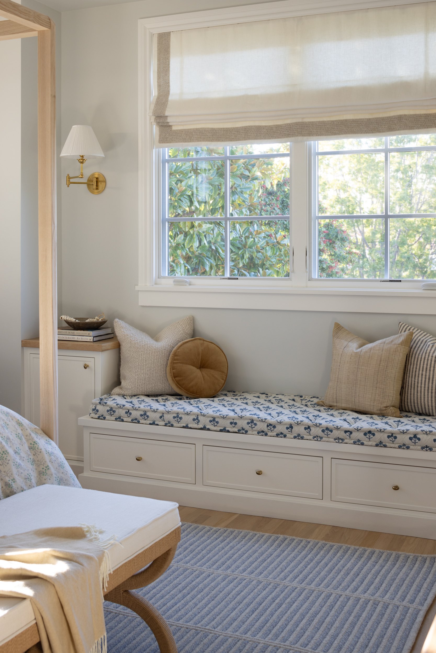 Comfortable window seat with cushions in a bright, airy interior.