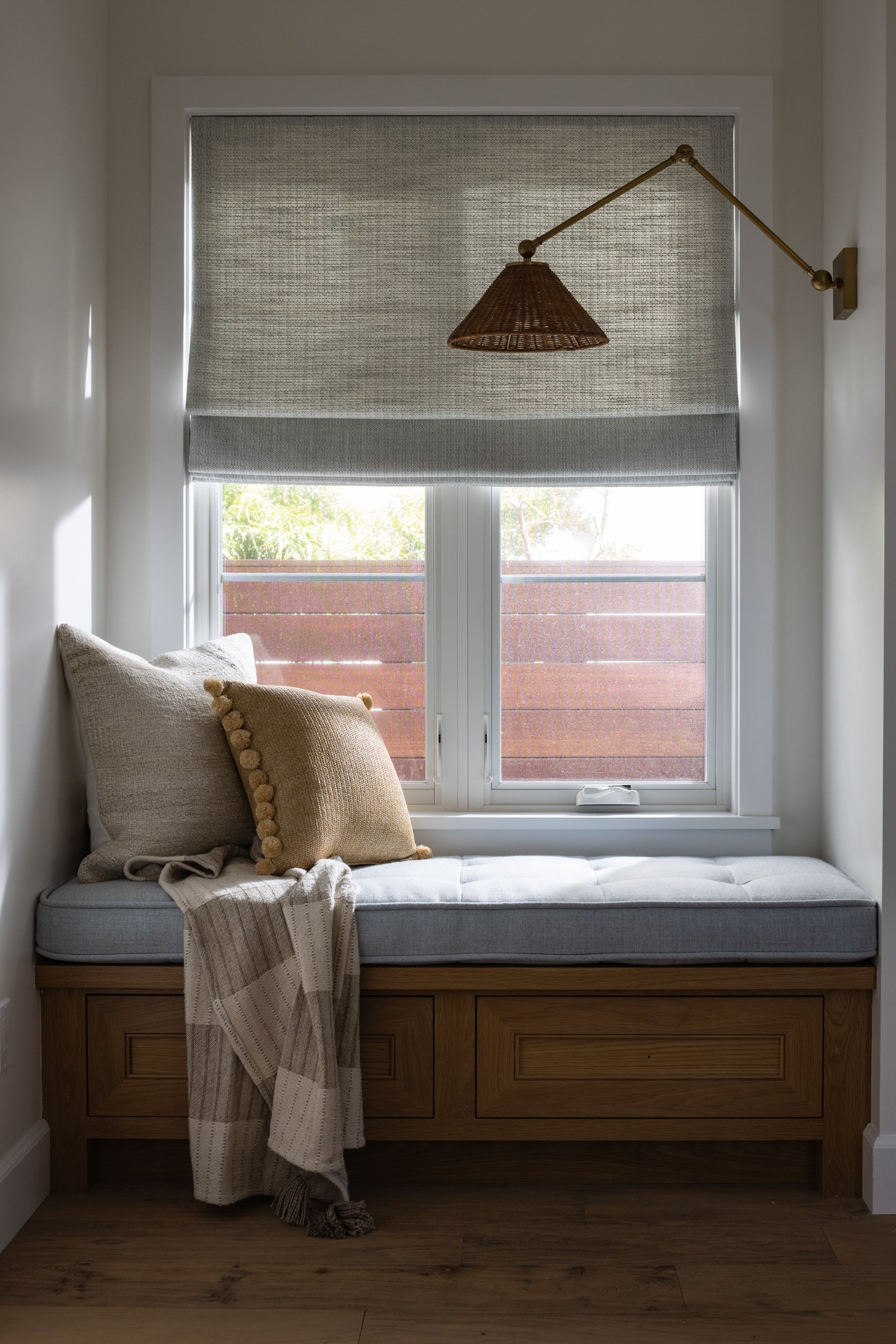 Elegant window seat with cozy cushions and a stylish wall-mounted lamp.