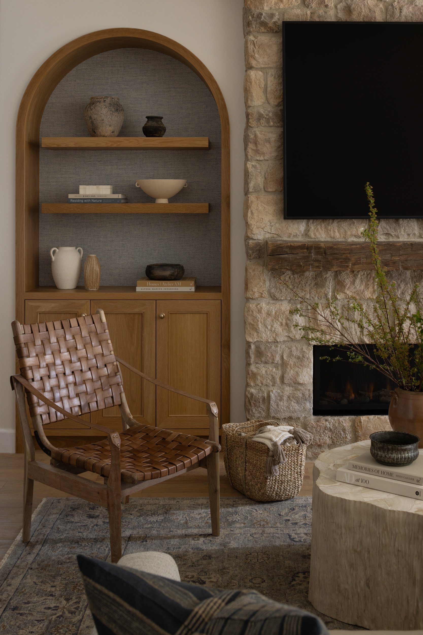 Modern living room with wooden shelves, stone fireplace, and contemporary decor.