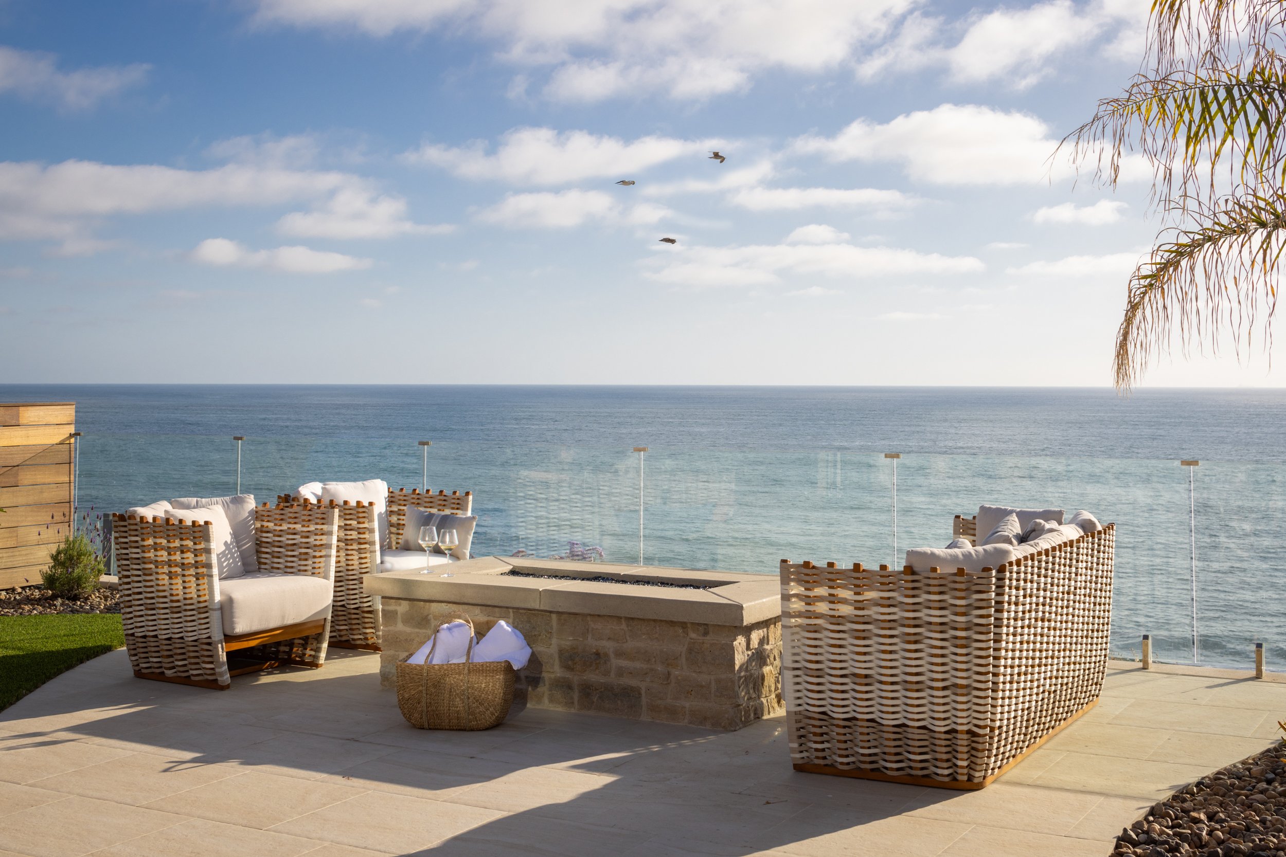Outdoor coastal lounge with wicker furniture and ocean view.