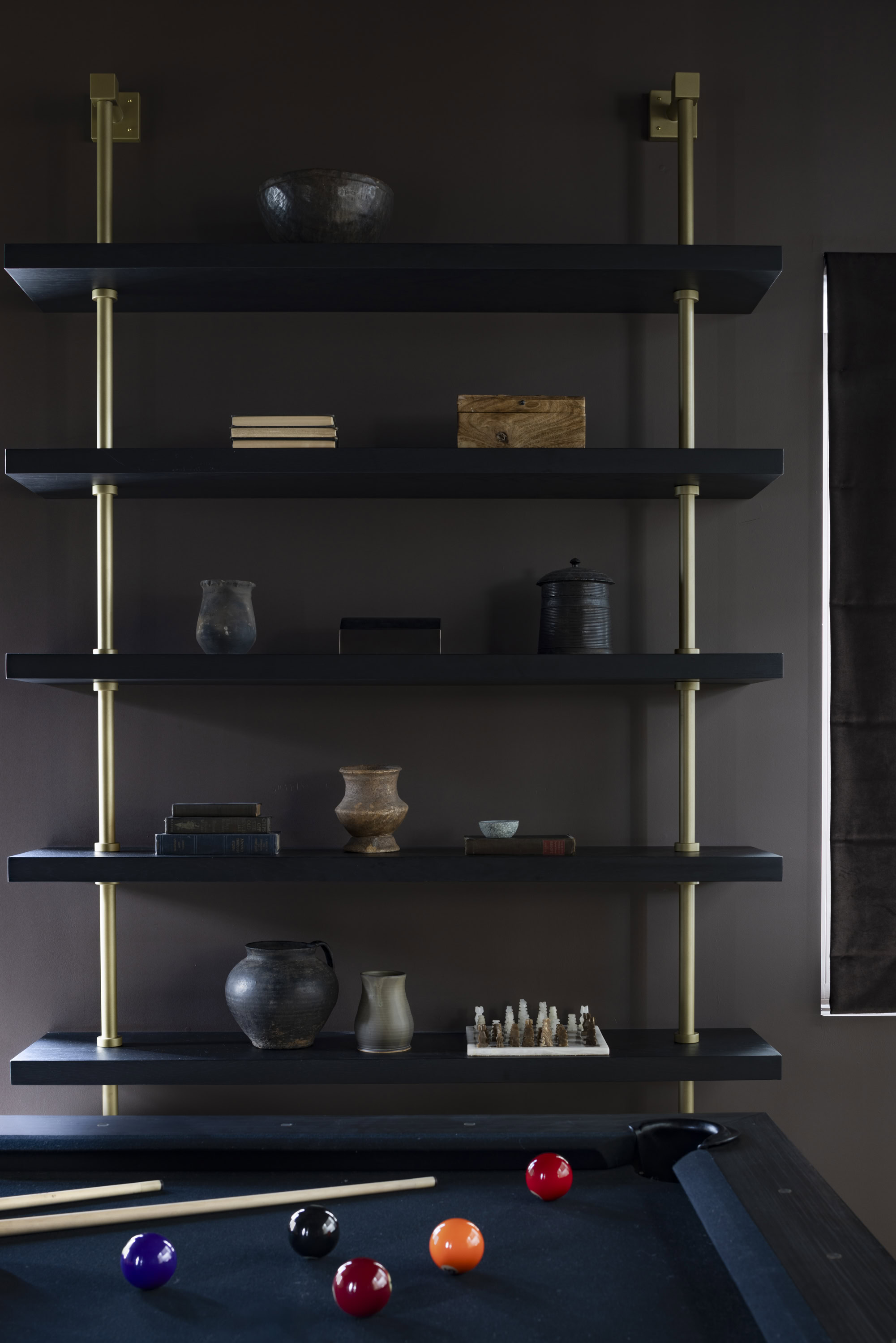 Stylish black wall shelves with decorative vases and books in a contemporary living space.