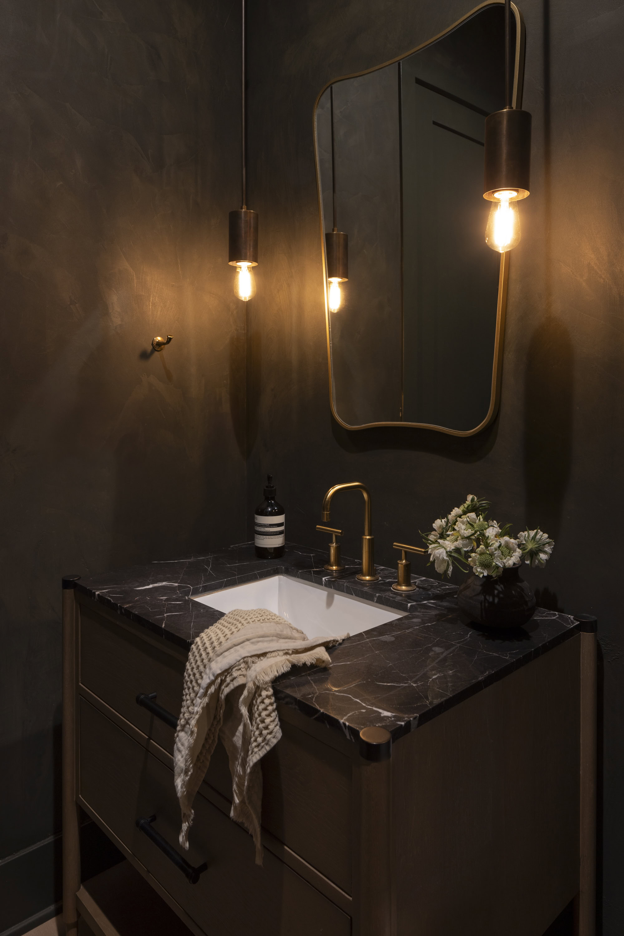 Luxurious bathroom interior with dark walls, stylish mirror, and modern lighting fixtures.
