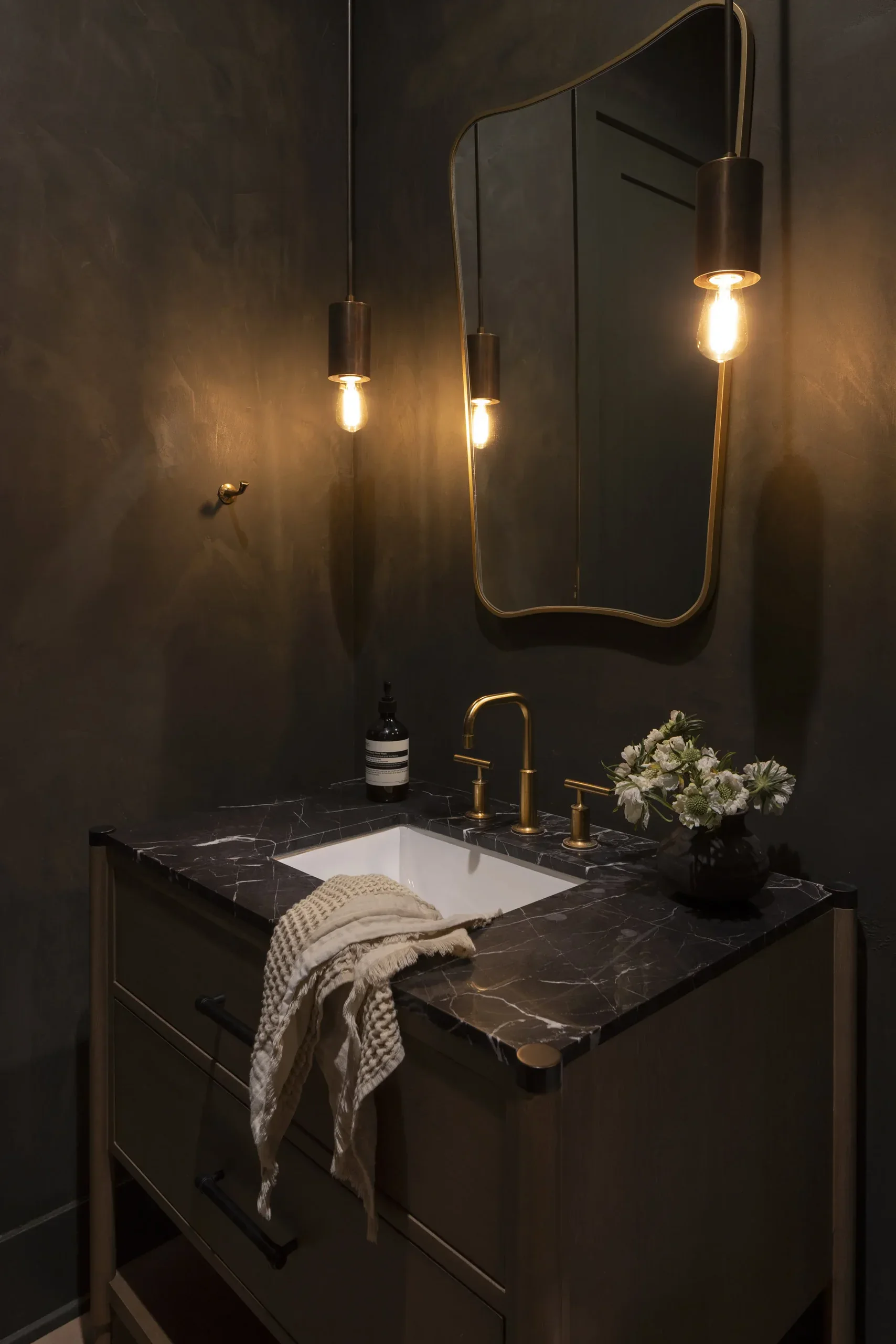 Luxurious bathroom interior with dark walls, stylish mirror, and modern lighting fixtures.