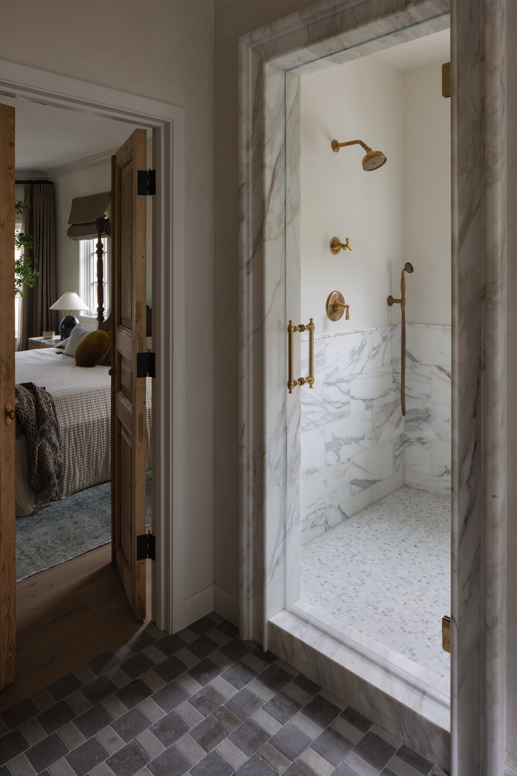 Luxurious walk-in shower featuring marble walls and gold fittings, part of the Vista Claridad interi.