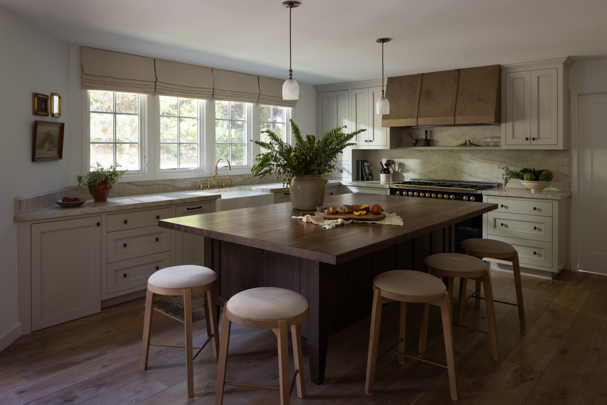 Bright kitchen featuring large windows, white cabinetry, and a central island for cooking and gather.