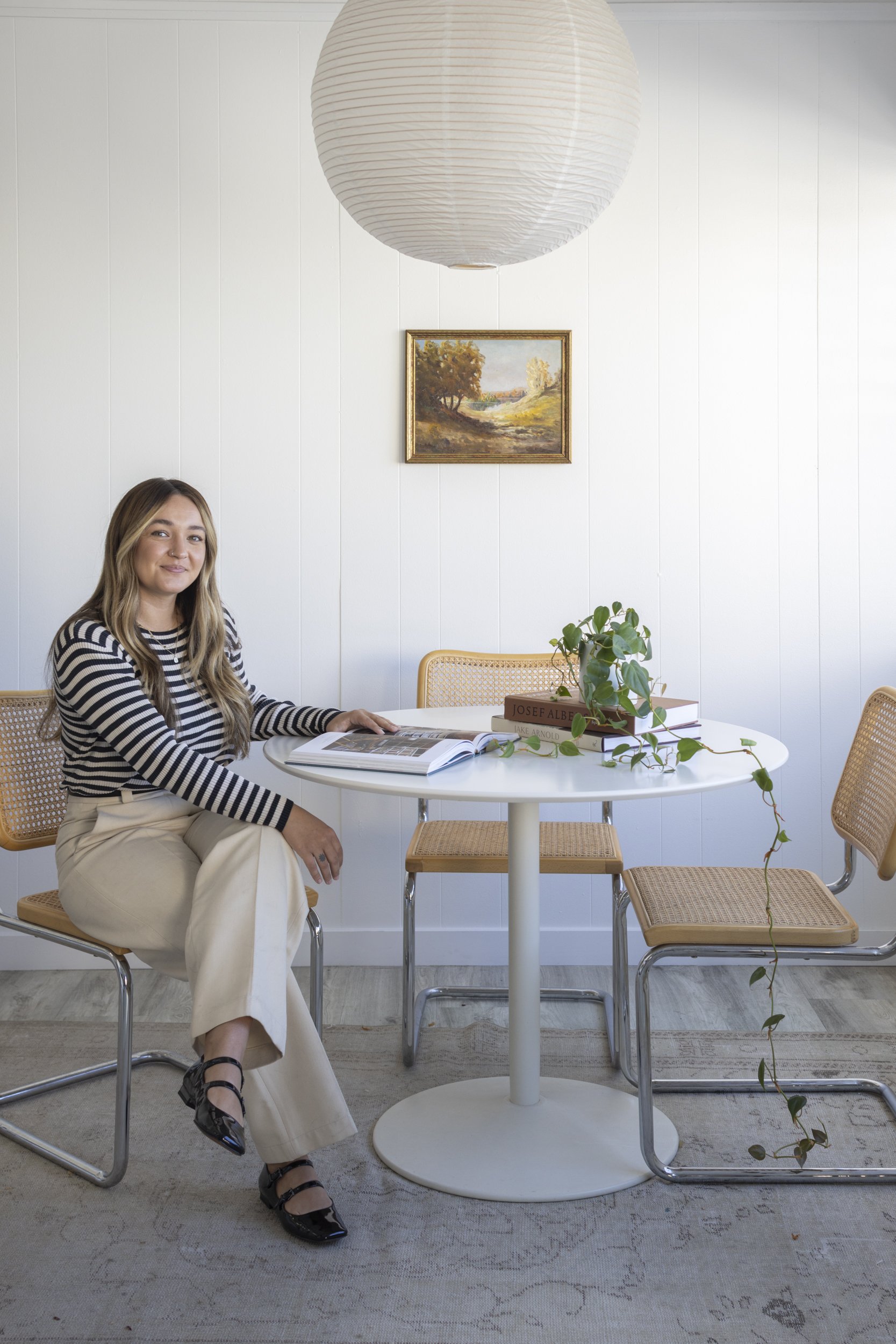 Woman sitting at a table in a modern, bright interior with minimalist decor.