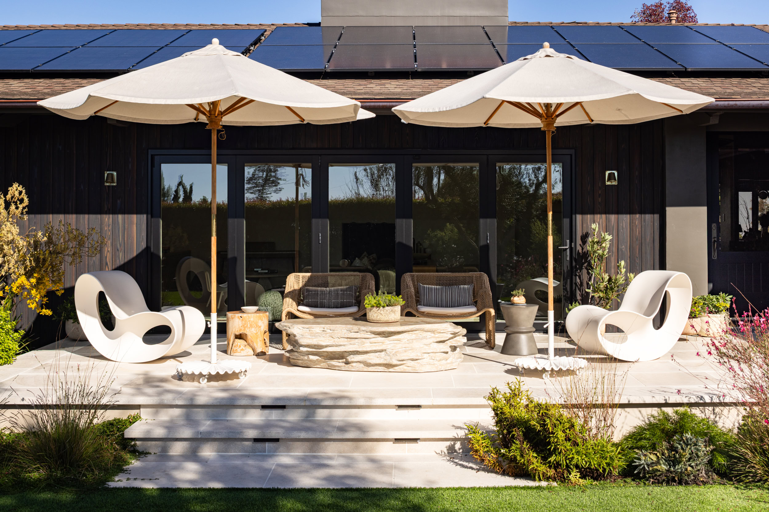 Outdoor patio furniture with umbrellas and lush plants for a cozy home garden setting.