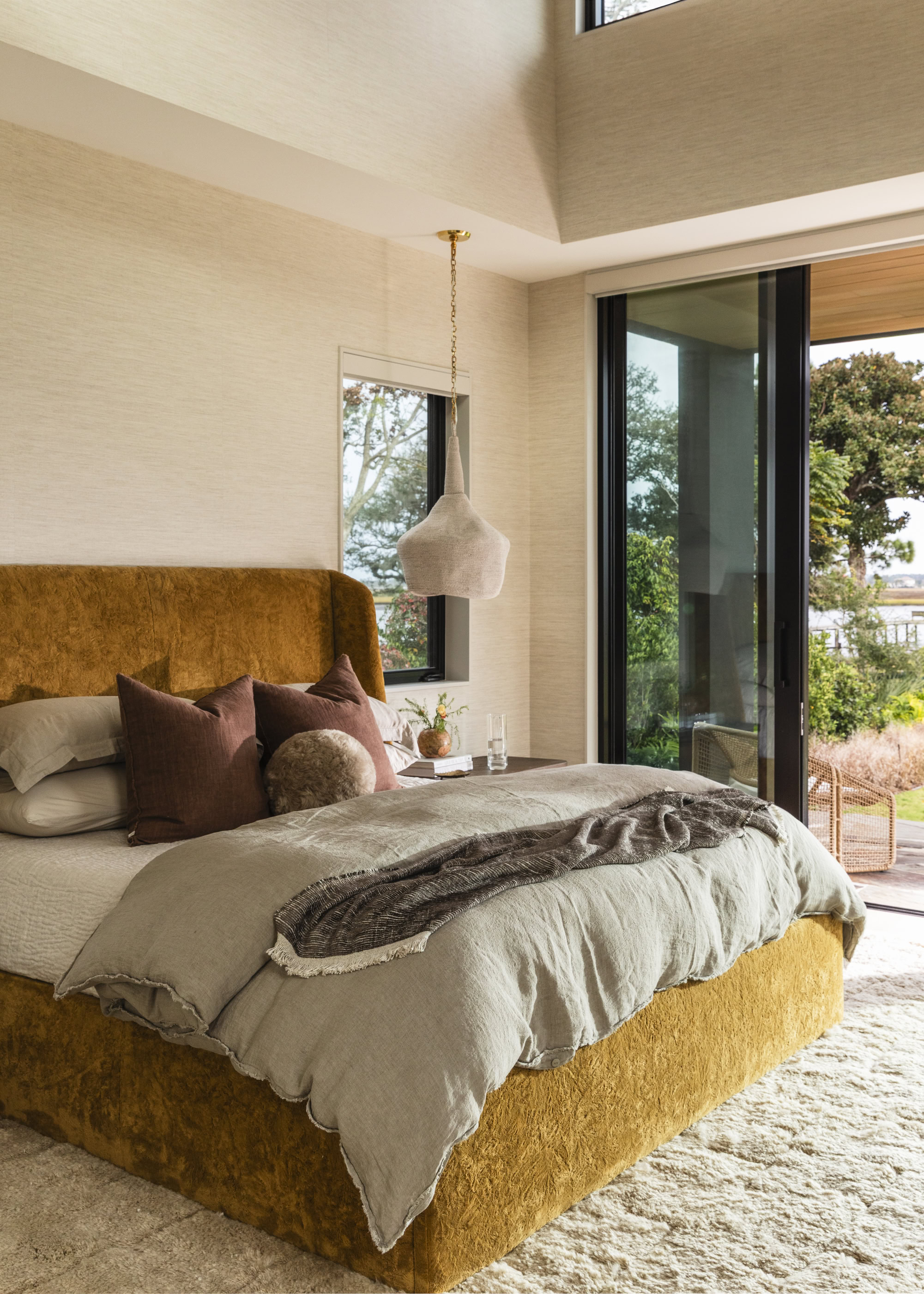 Modern bedroom with large windows, natural light, and stylish decor for a comfortable living space.