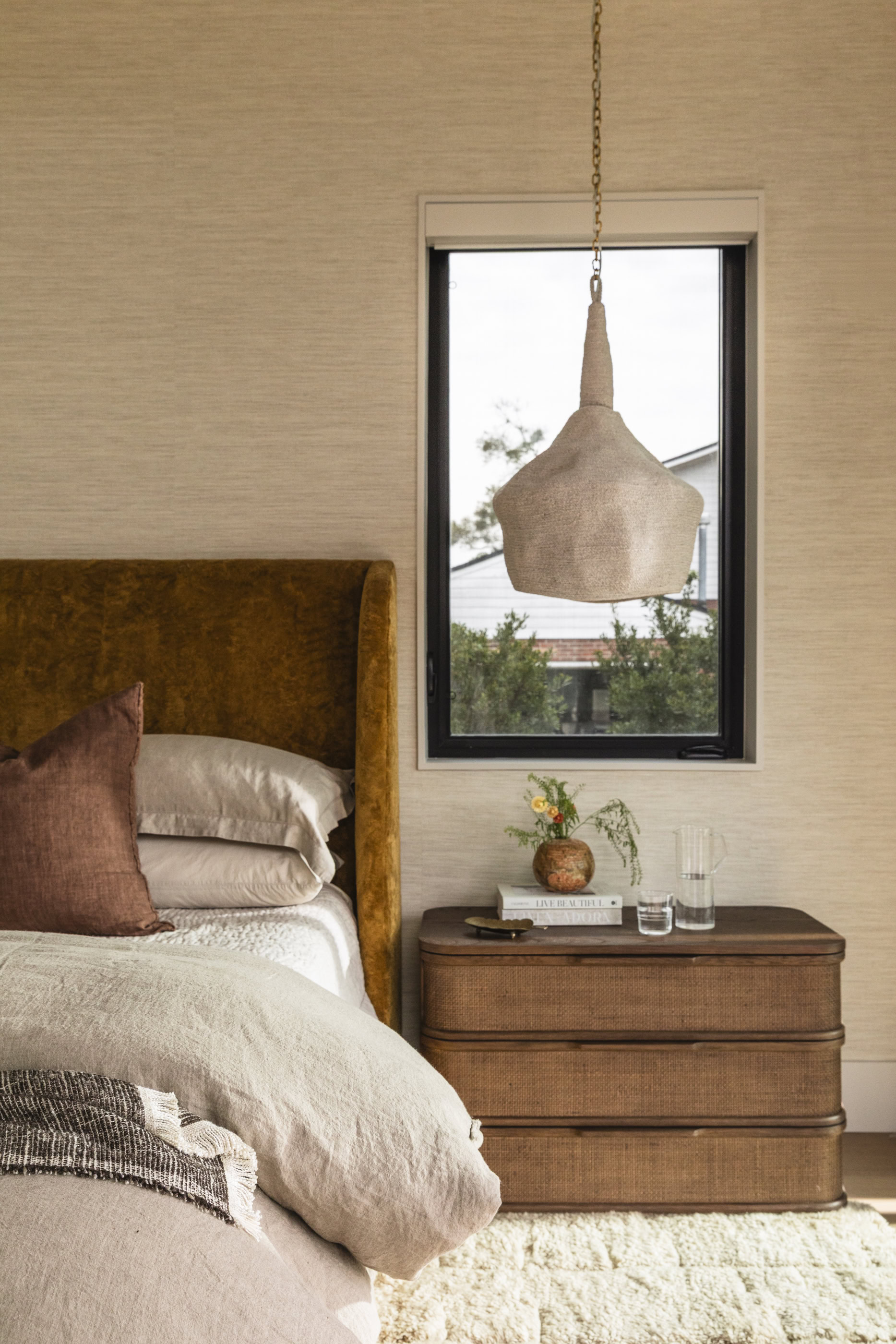 Elegant bedroom with modern pendant light and cozy bedding.