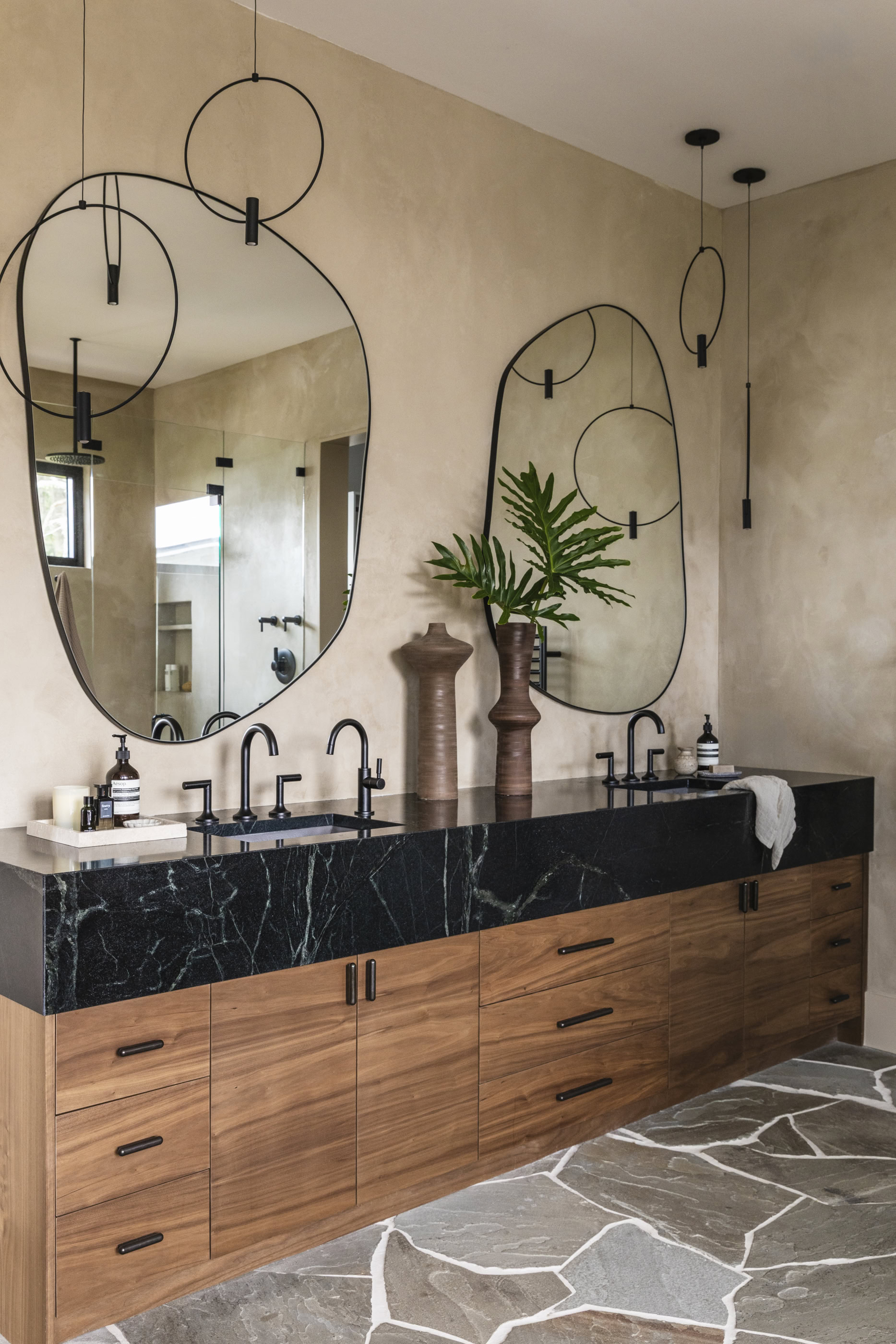 Stylish bathroom vanity with black marble countertop, wooden cabinets, and decorative mirrors.