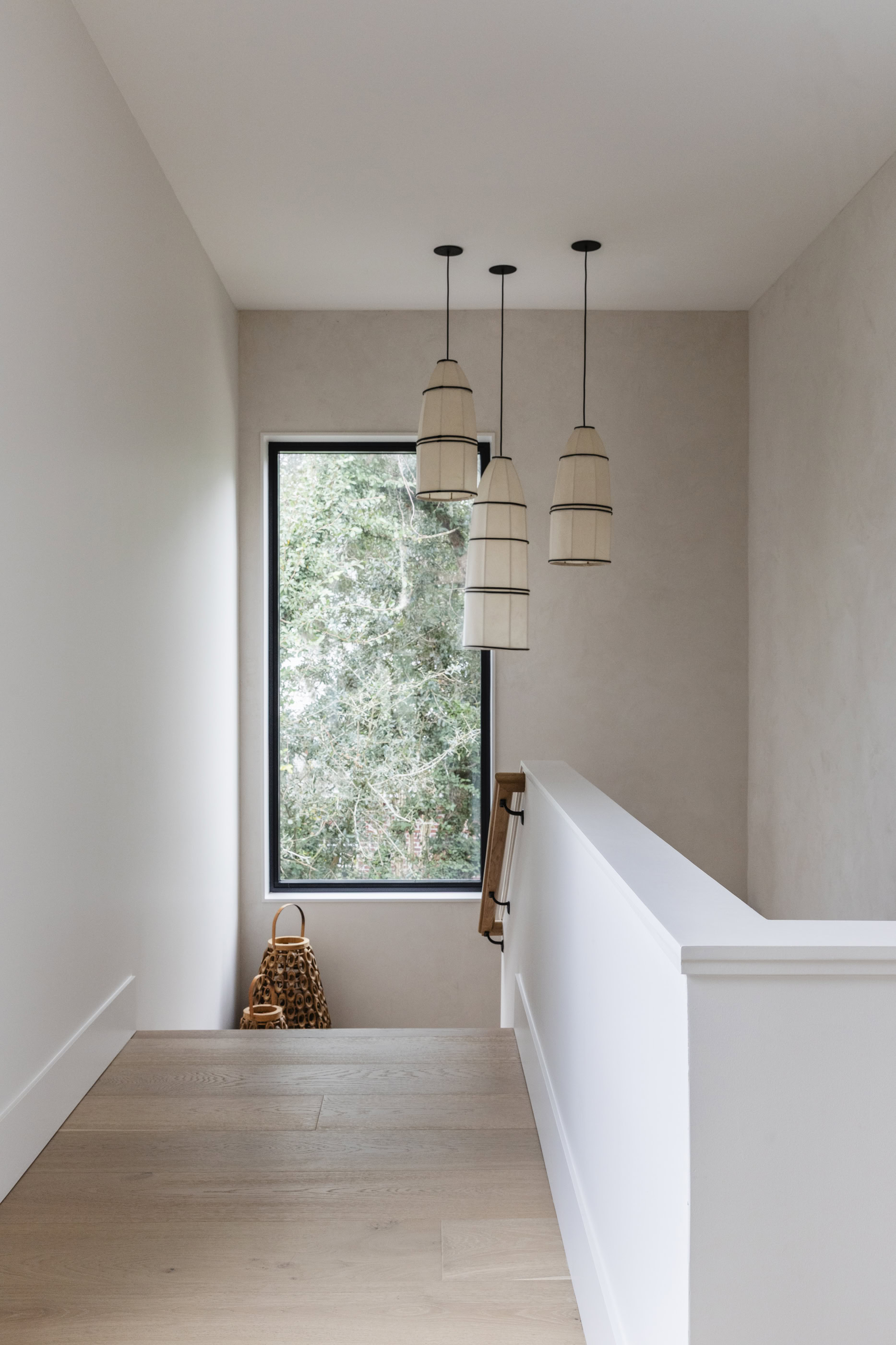 Modern staircase with stylish pendant lights and a large window.
