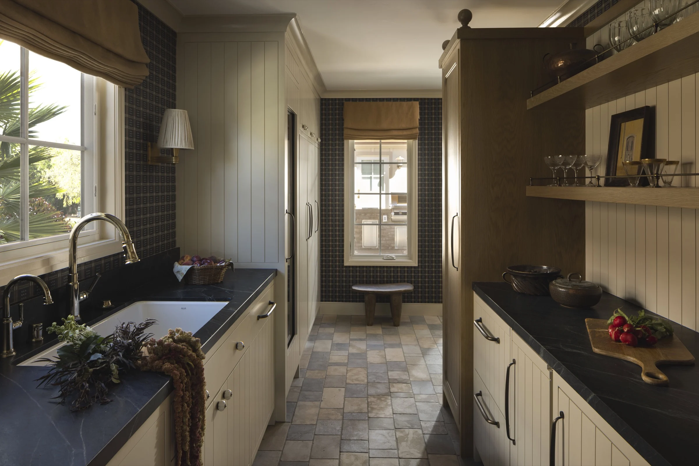 Bright kitchen with white cabinetry and black countertops, featuring natural light from large window.