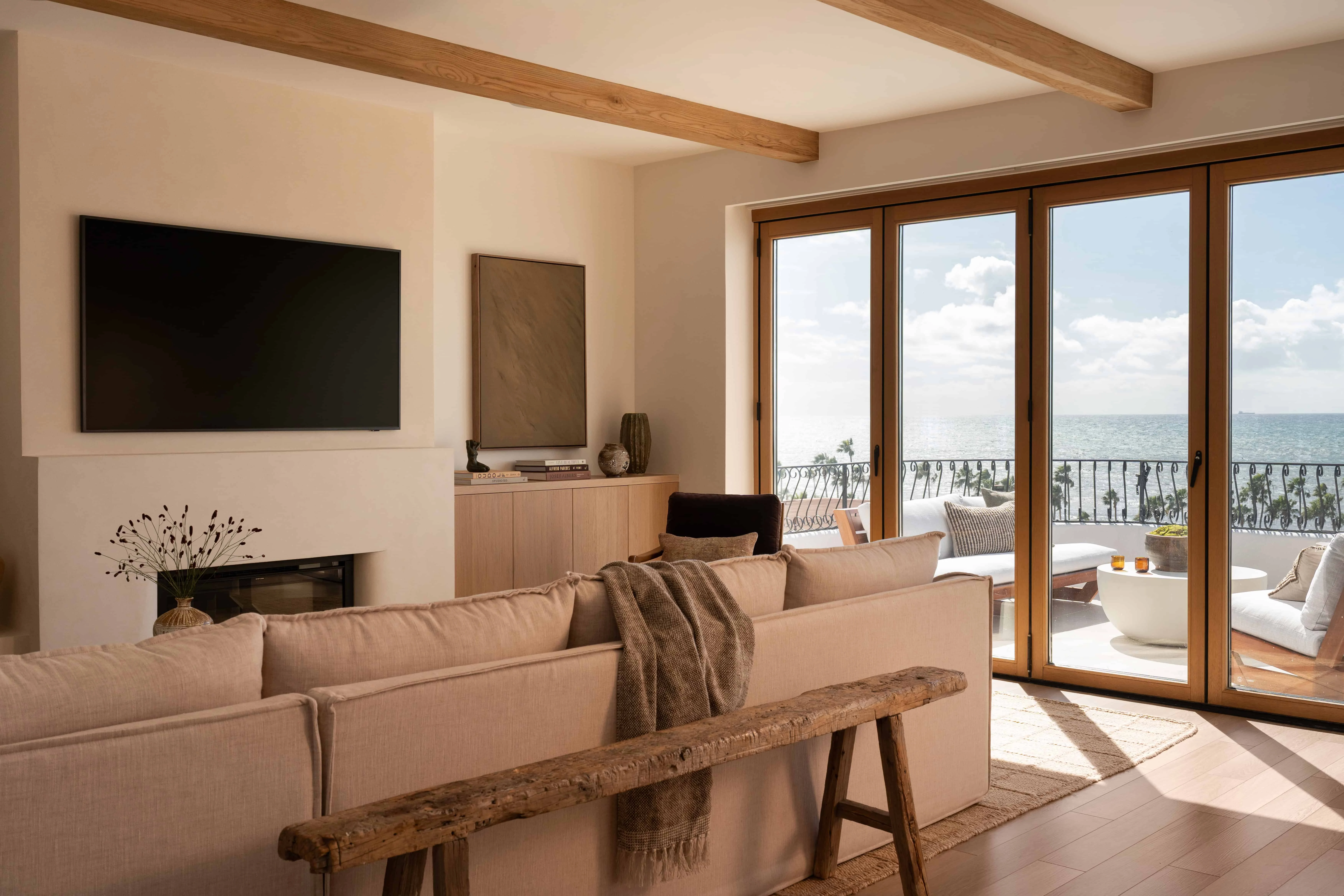 Modern living room with ocean view, large glass doors, and cozy seating.
