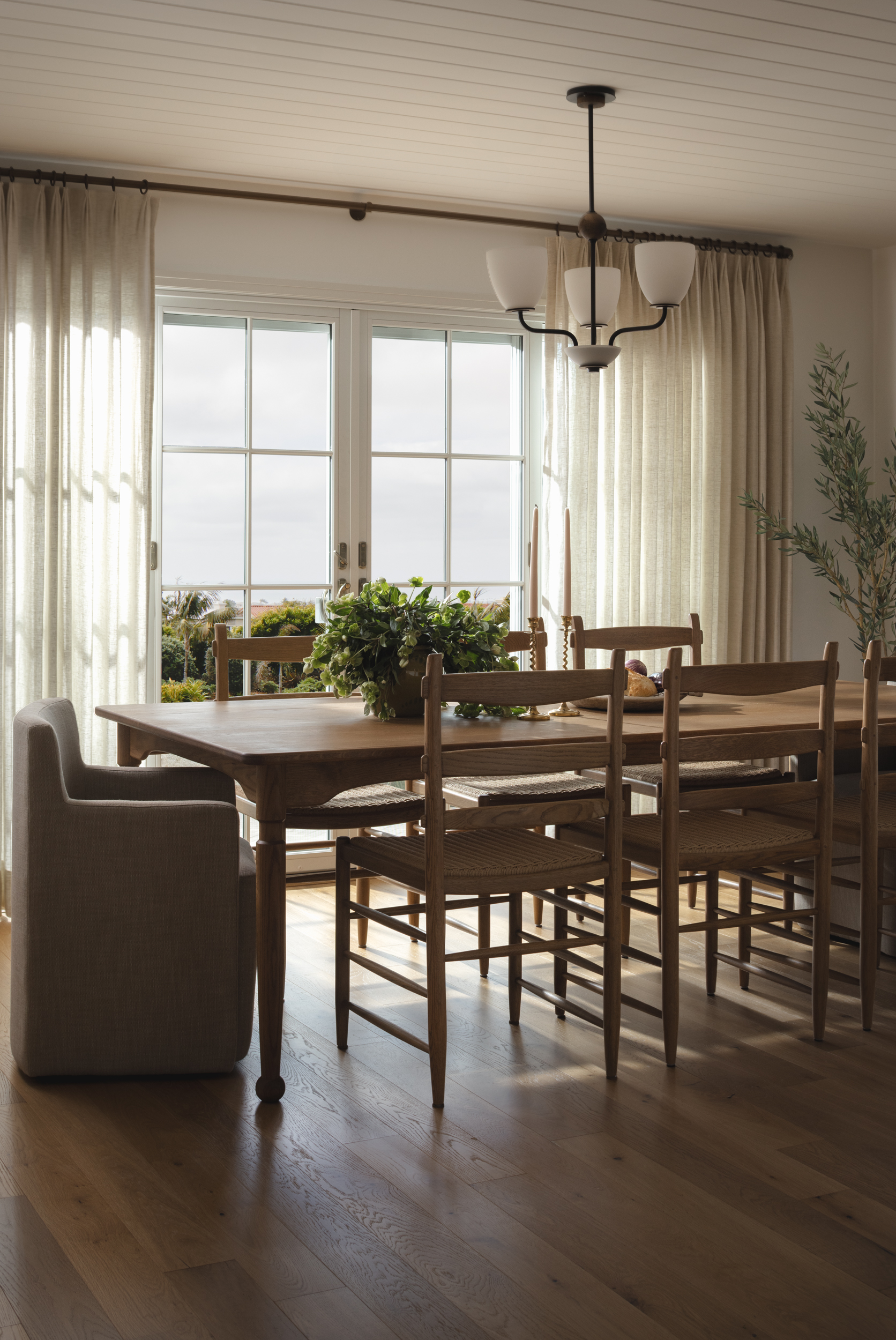 Elegant dining room with wooden table and chairs, large window, and neutral curtains.