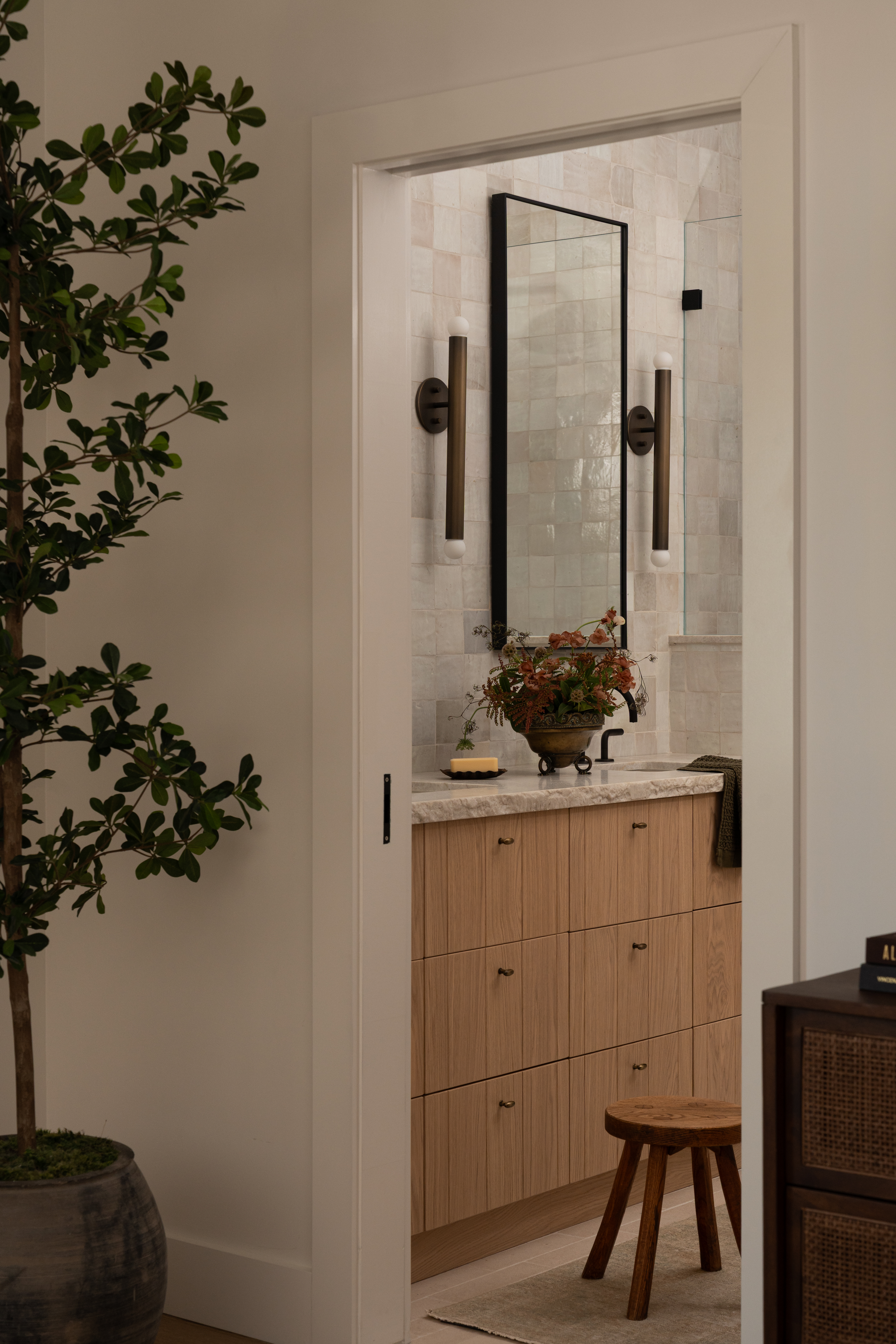 Modern bathroom with wooden vanity, mirror, and wall-mounted lights.