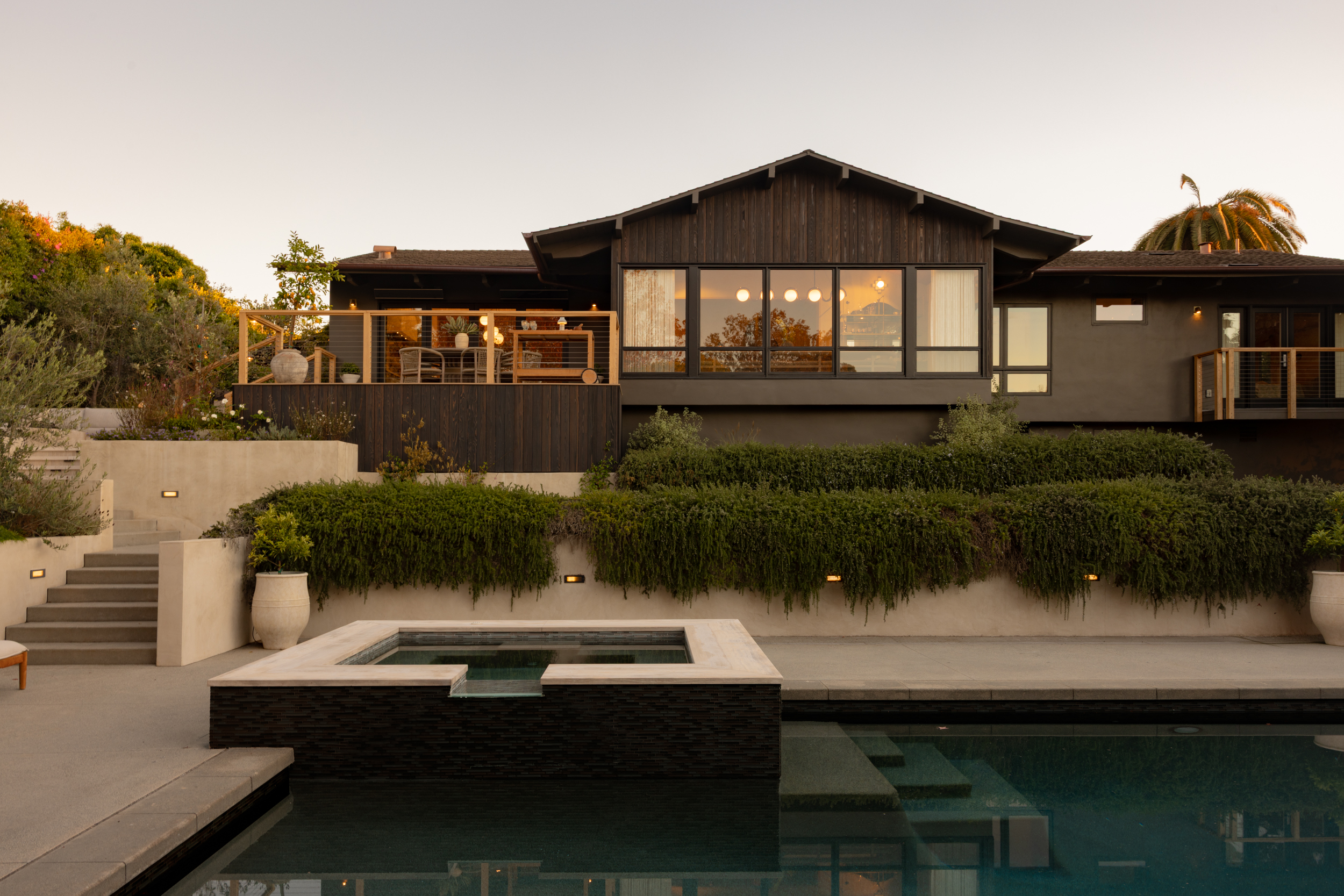 Modern house with large windows and outdoor pool at sunset.